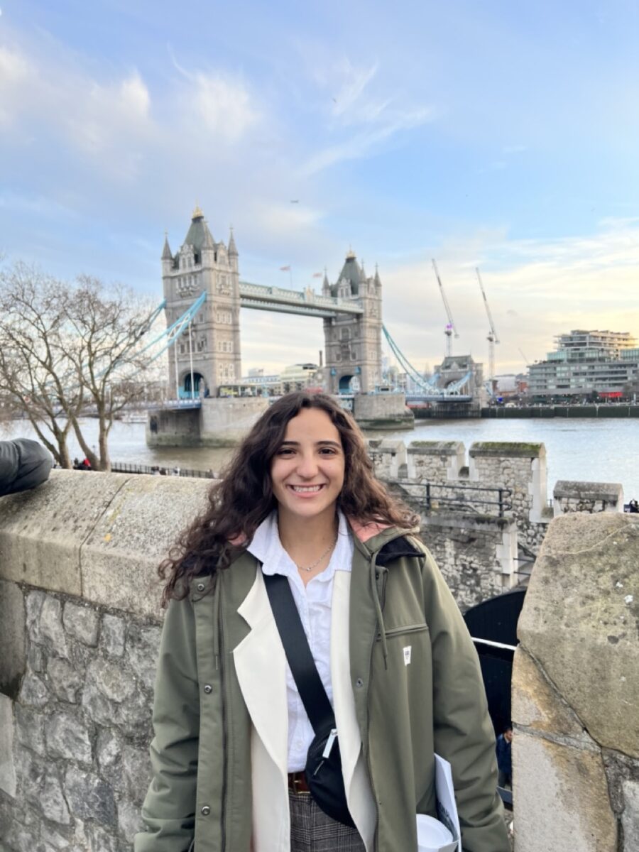Young woman standing by the Thames river with Tower Bridge in the distance