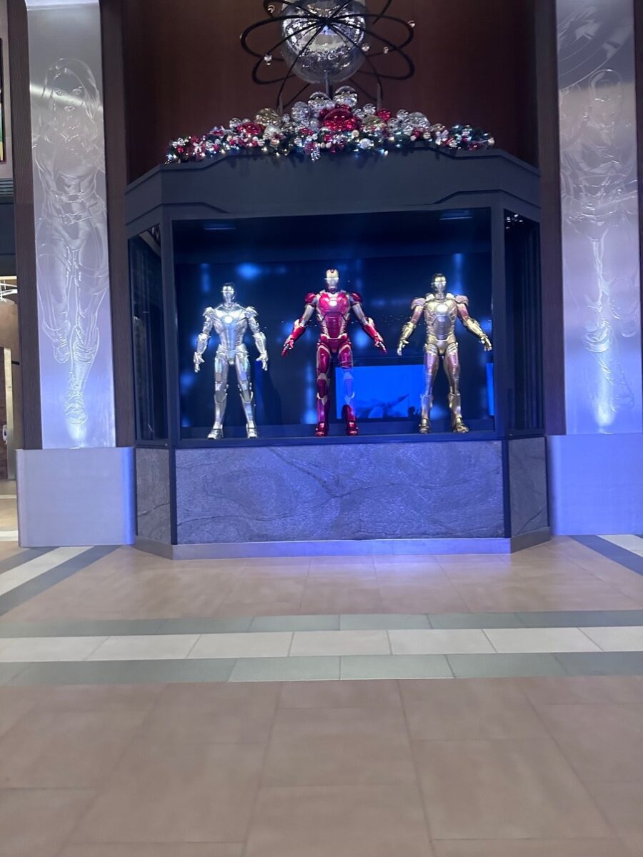 Three futuristic suits of armor in a display inside a large hotel lobby.