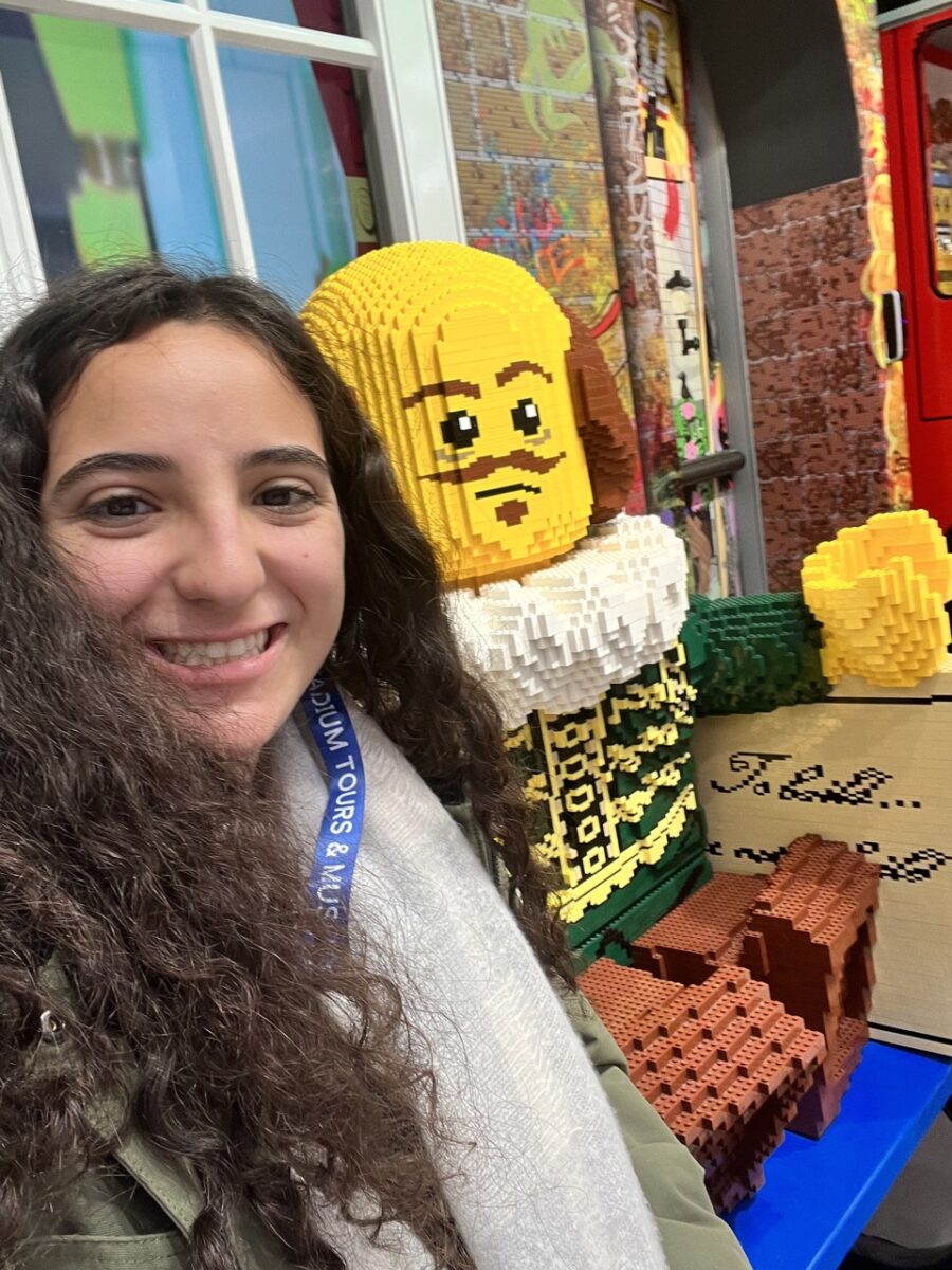 Young woman sitting beside a life-size LEGO Shakespeare figure
