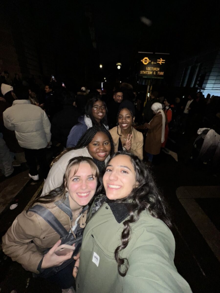 Young women wearing winter coats posing for a group selfie at night