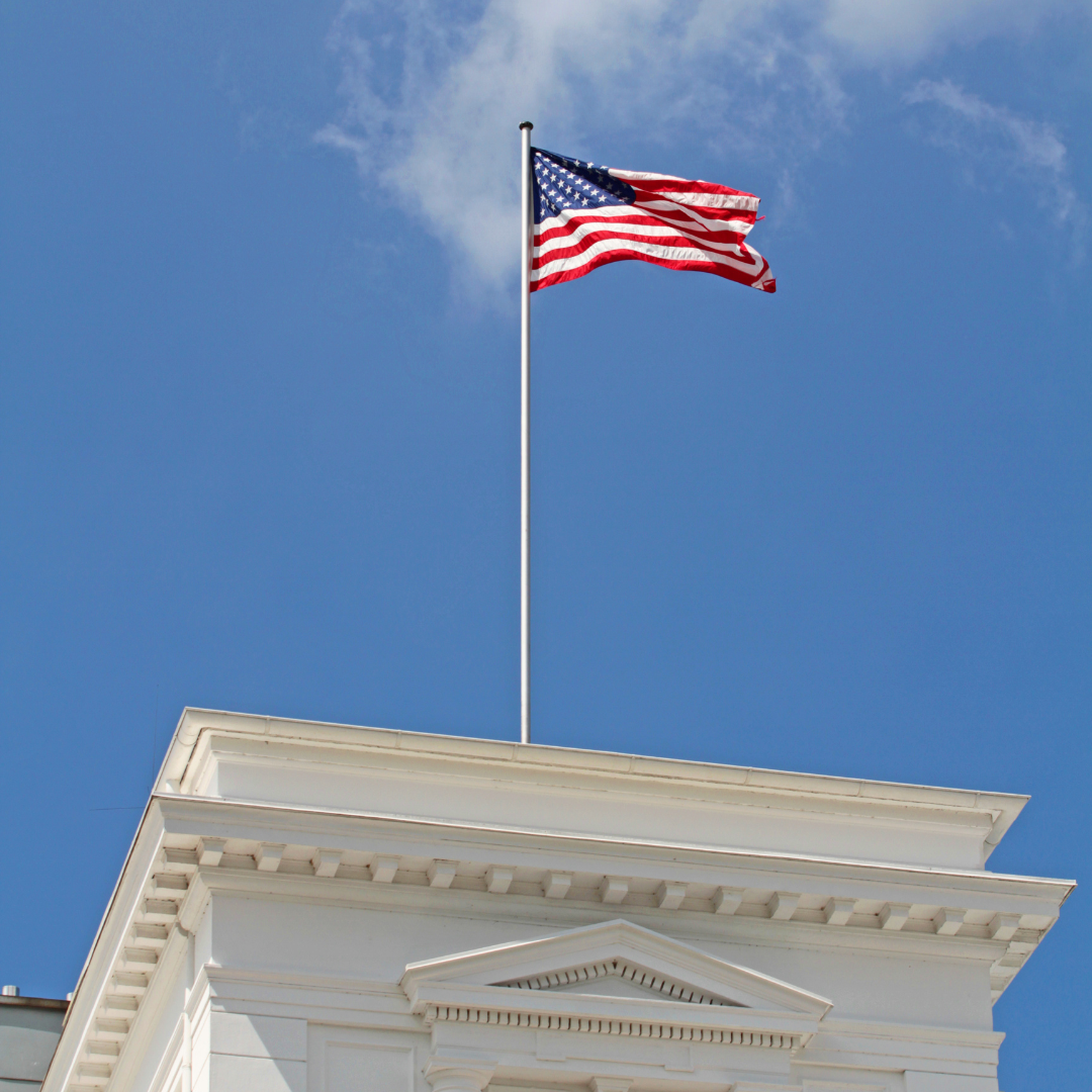 American flag waving on a flagpole atop a white building.