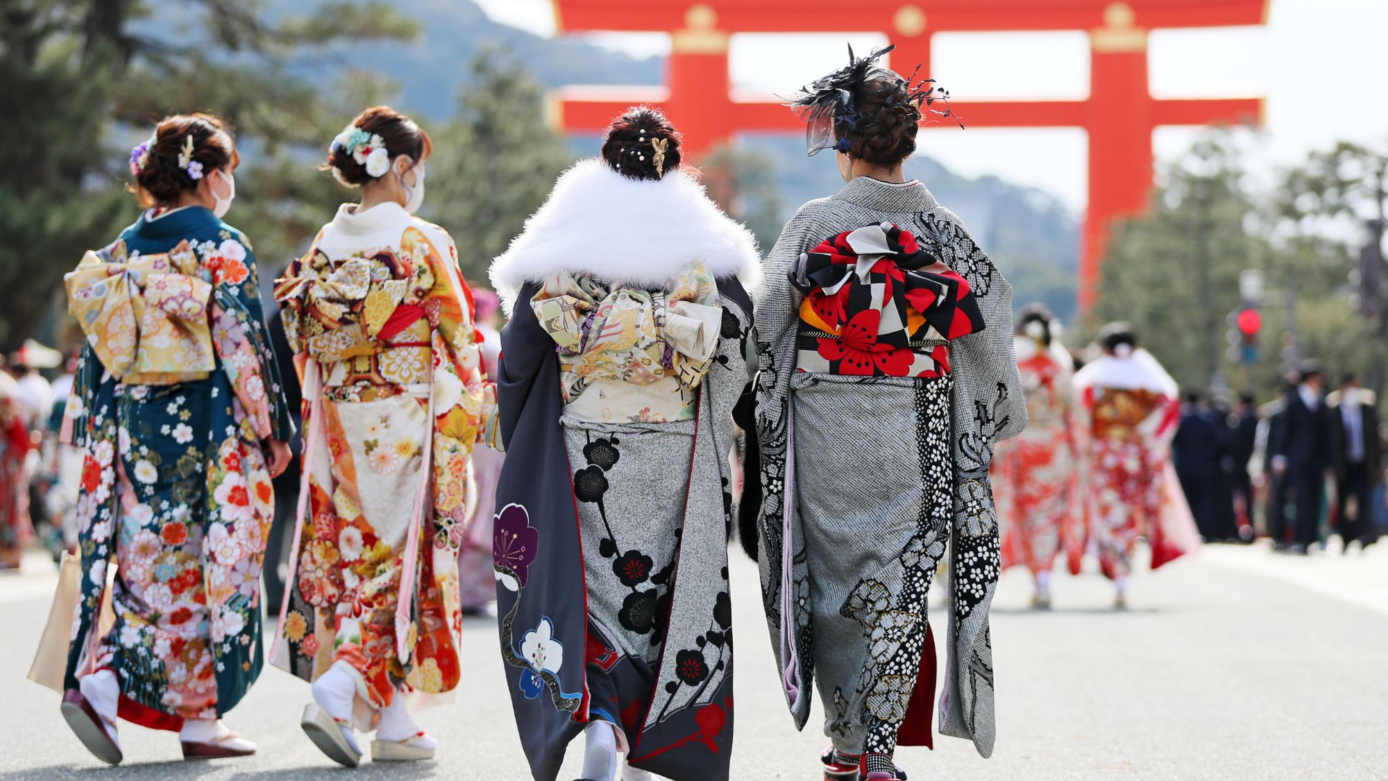 Four women wearing yukata walking toward a torii.